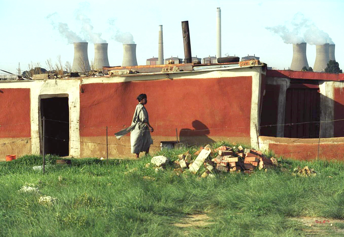 A woman stands in front of the Matla coal power plant.