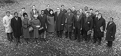 An old black and white photo shows a large group of educators standing outdoors in a group to pose together.