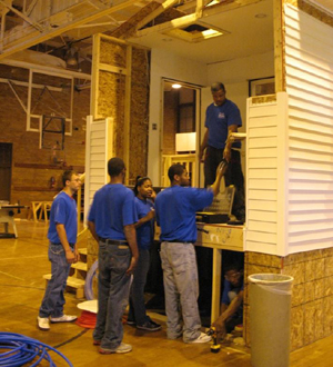 A group of students work on a mock building in a classroom setting.