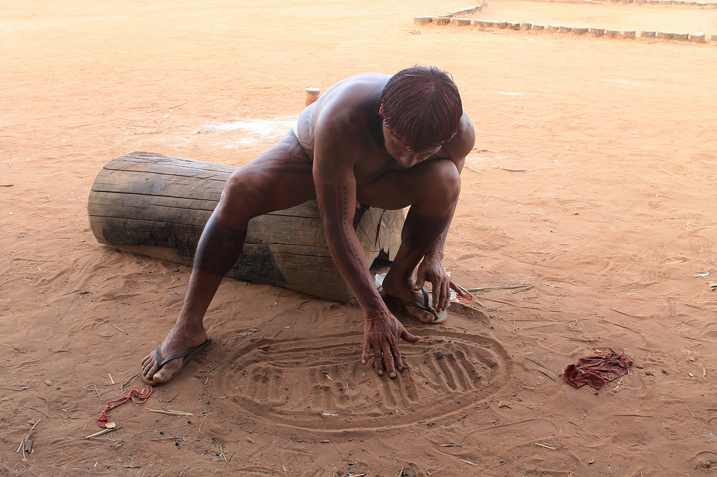 Chief Yapatsiama draws in the dirt to illustrate how an electrical grid will connect solar panels in his village.