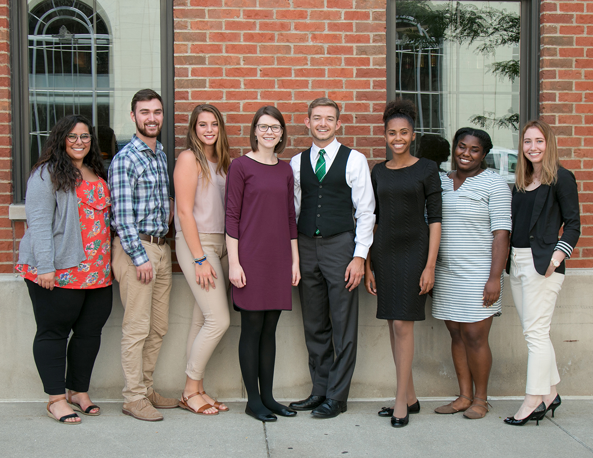 Mott's 2017 intern cohort pose in a line in front of a brick building.