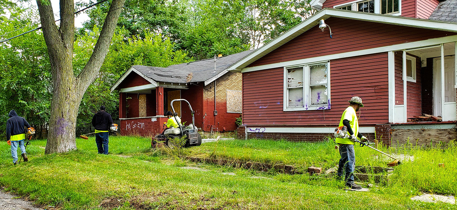 A crew works to clean up lawns in front of houses.