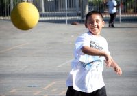 An action shot of an elementary-aged boy throwing a ball toward the general direction of the camera.