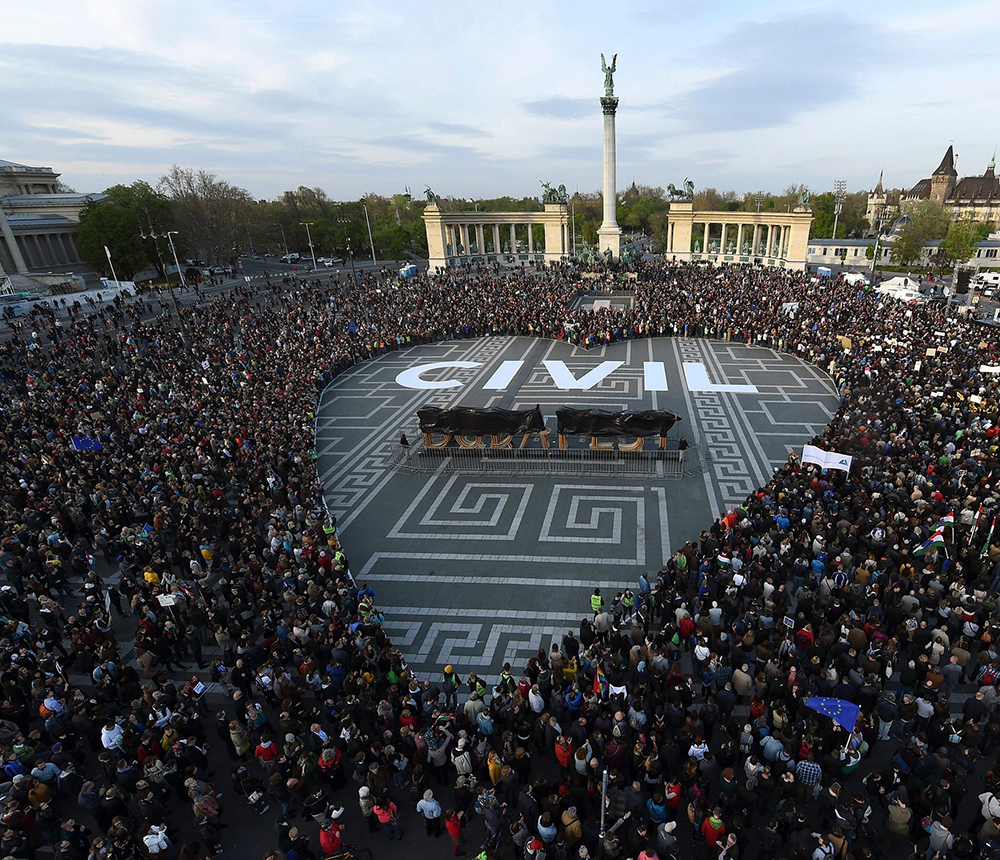 Protesters at Heroes' Square in Budapest form the shape of a heart with the word "CIVIL" in white letters on the ground in the center of the heart.