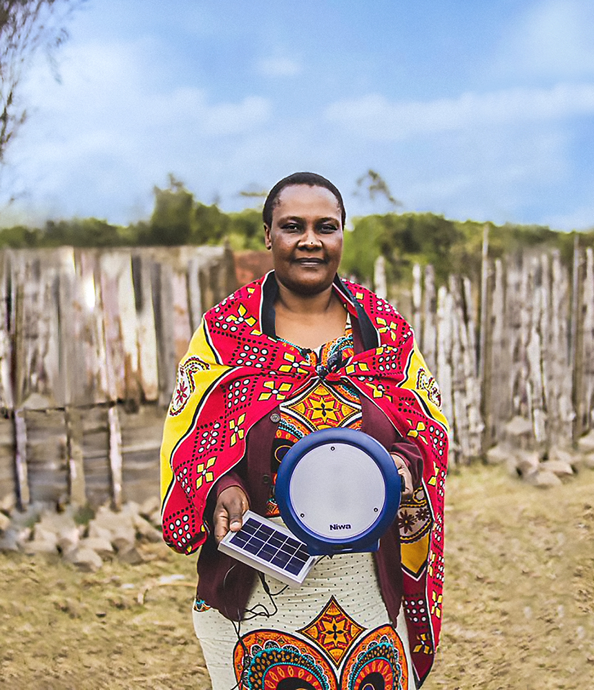 A woman wearing vibrant patterns holds a solar lantern she received from Nguzo Africa’s green energy project.