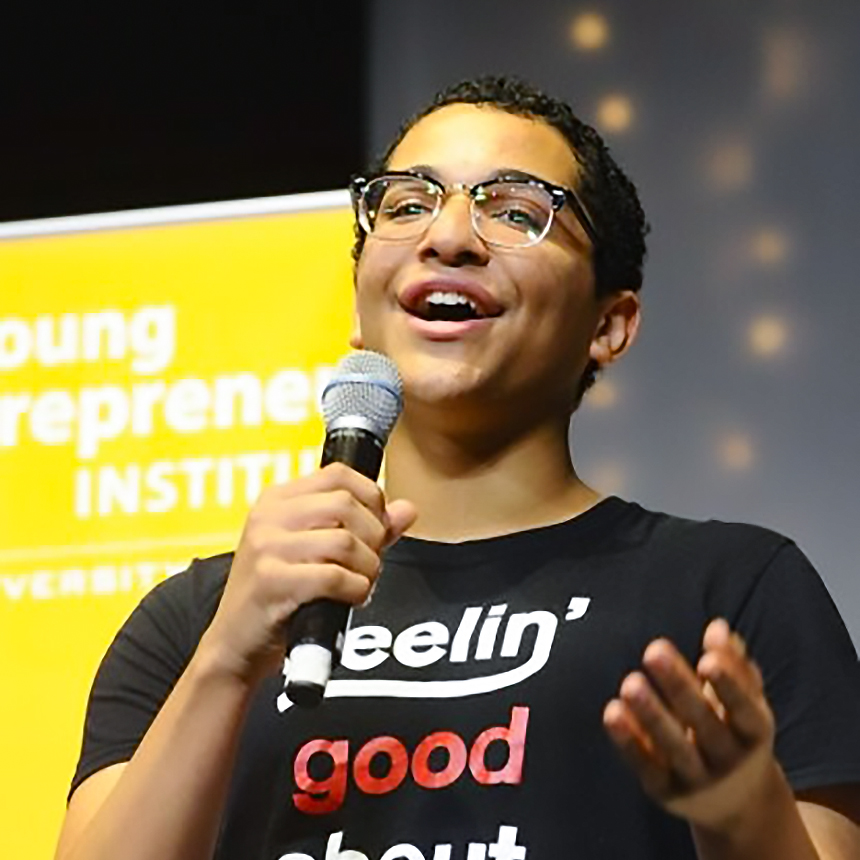 A young person speaks into a microphone while giving a presentation at Young Entrepreneur Institute.