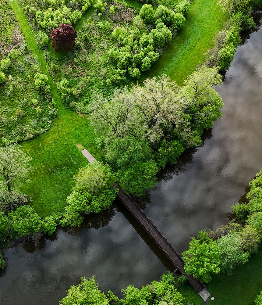 Drone footage of the Flint River is filled with green foliage and a reflection of clouds on the water.