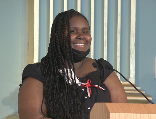 A smiling teen girl stands at a podium.