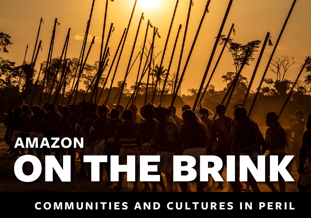 A group of Kayapó, Indigenous people who live in dispersed riverside villages, are shown marching to protest destructive development in the Amazon. Text reads Amazon on the brink: Communities and cultures in peril.