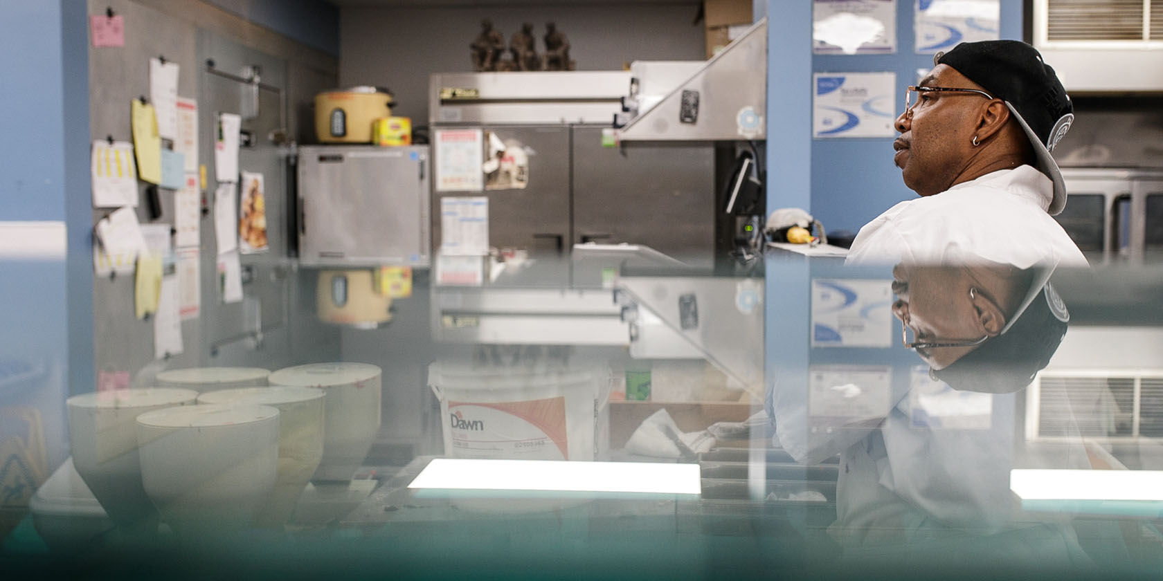 A man looks over the counter in an industrial kitchen.