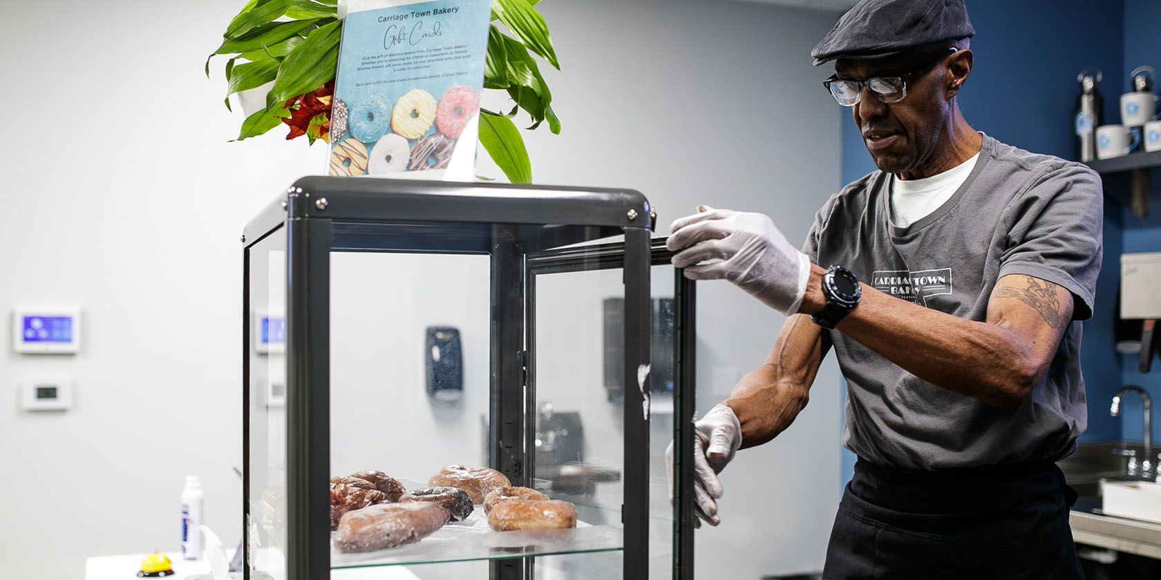 A man prepares a display case full of doughnuts.