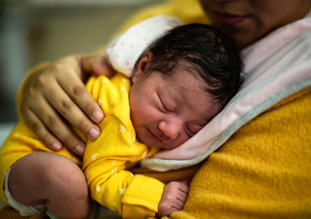 Portrait of a newborn baby girl held by her mother.