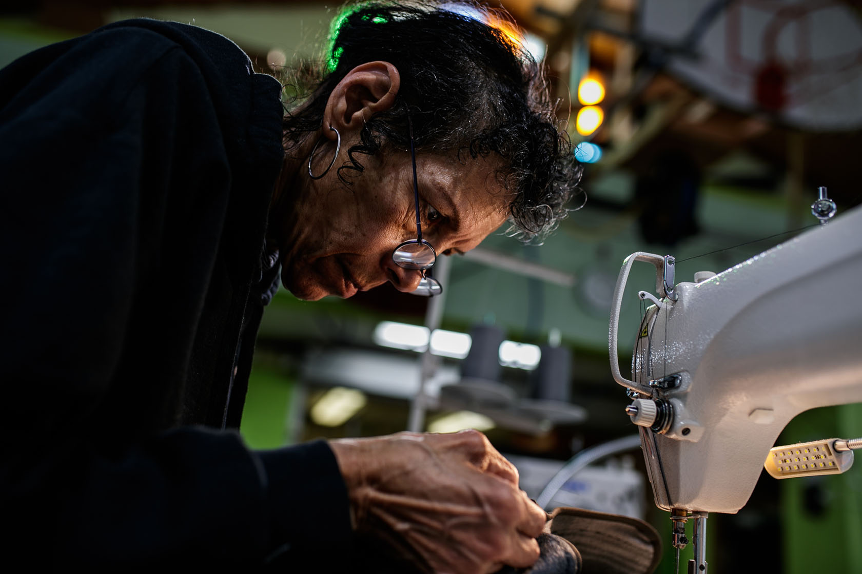 A woman sews a vest at at Juki sewing machine while smiling down at her work.