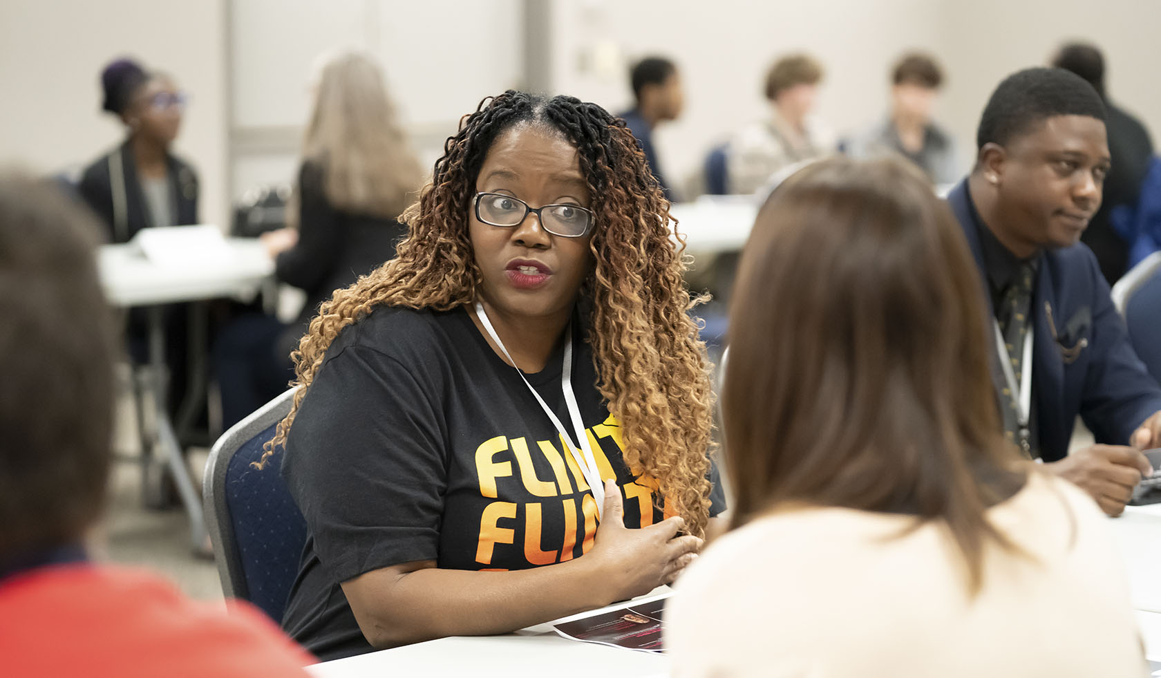 Mentors sit with groups of students in a room and discuss ways for students to discuss best practices for becoming successful entrepreneurs.