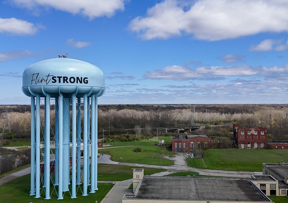 Pictured is the water tower in Flint, Michigan with the words "Flint STRONG" written on its light blue dome.