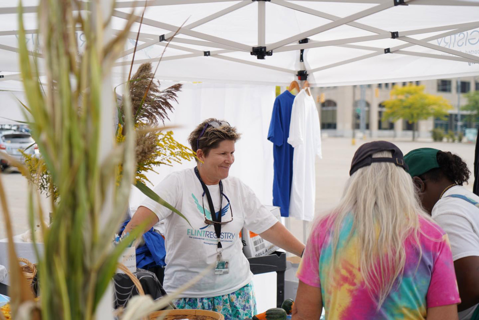 Lisa Pasbjerg, outreach and engagement coordinator at the Flint Registry, talks with community members about the organization and its resources while standing under a pop-up tent, at an event in downtown Flint.
