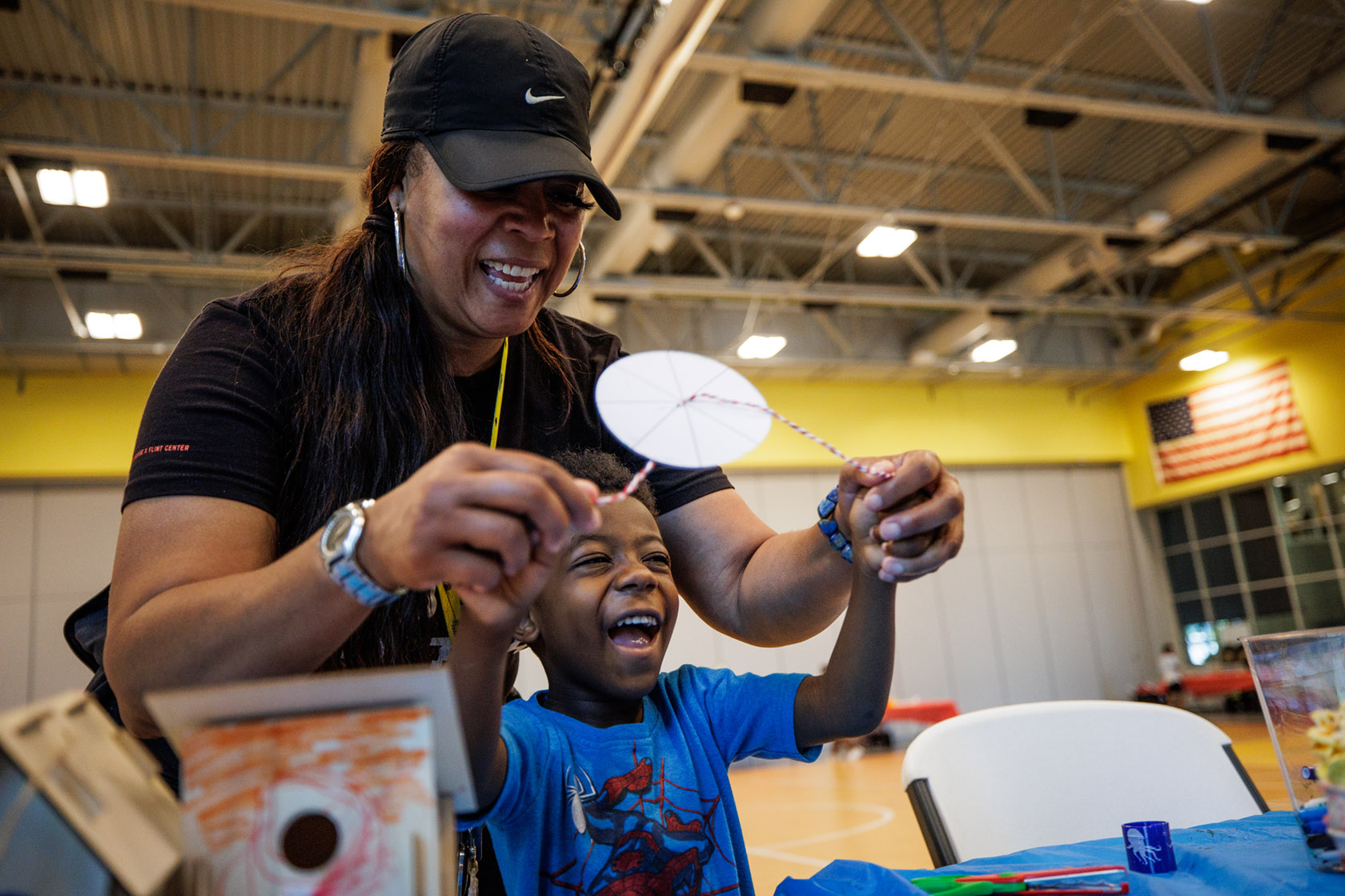 A Flint student spins a paper and string disk made as a craft with the help of a mentor at the Flint Cultural Center Academy.
