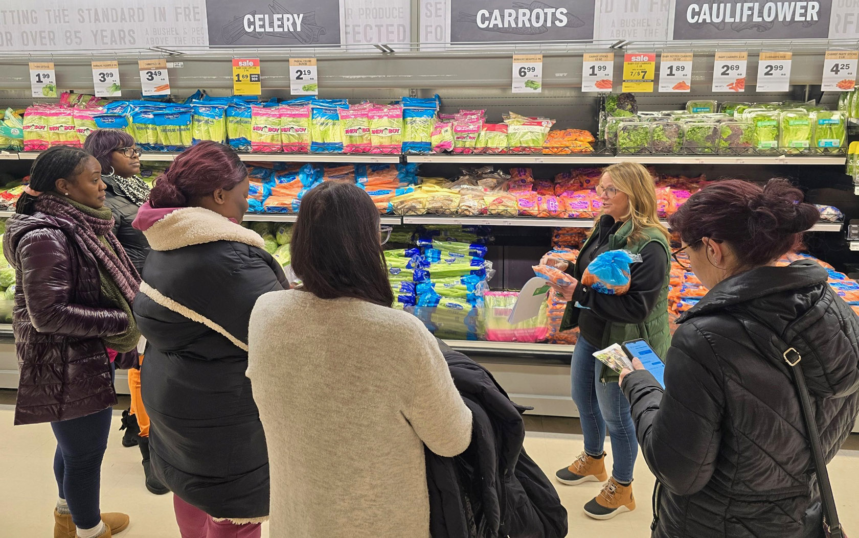 Women visit a grocery store vegetable section to talk and learn about healthy and nutritious food.