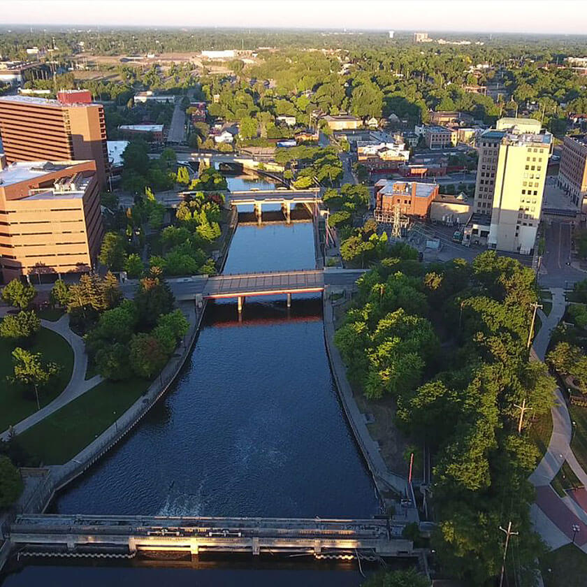 Drone footage looks over a river that runs through a city.