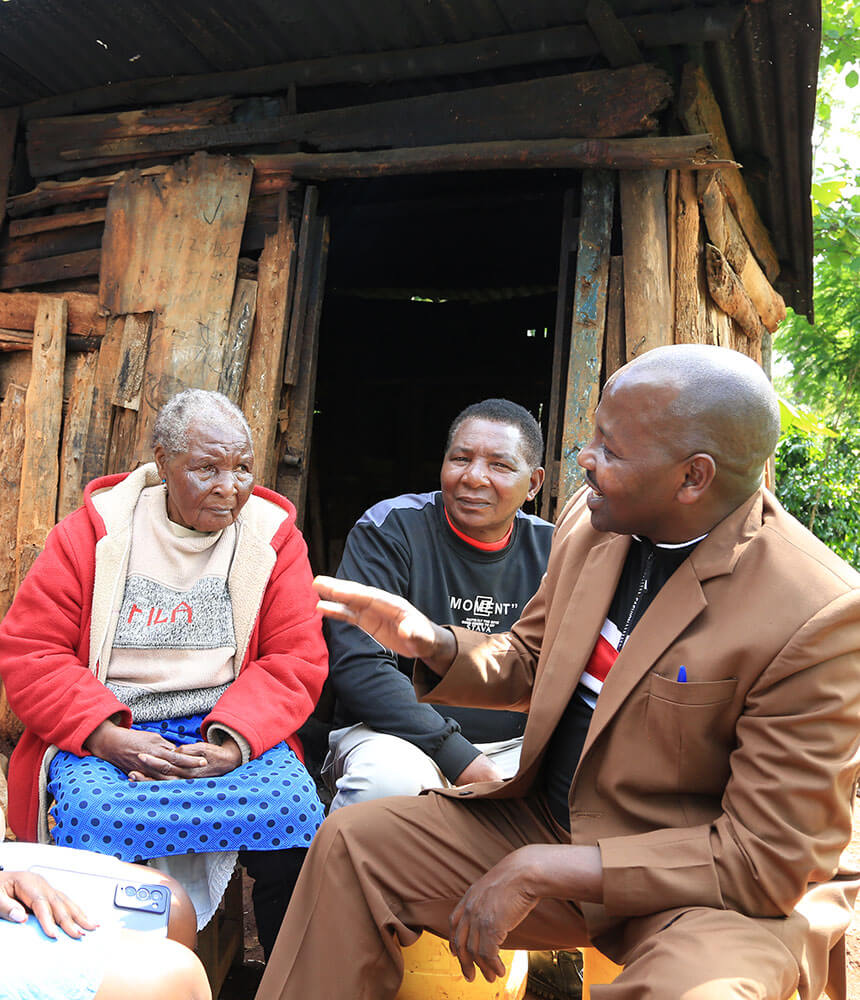 A man gives advice to an elderly woman in front of a wood building.