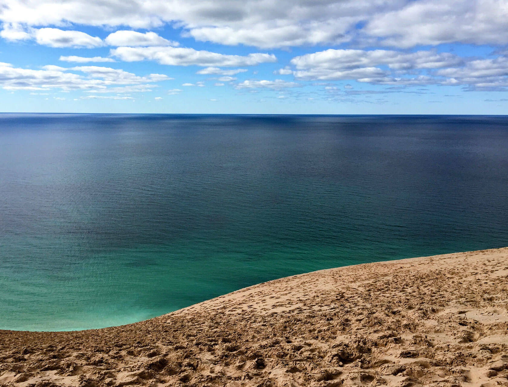 A lake shoreline fades into a cloudy blue sky on the horizon.
