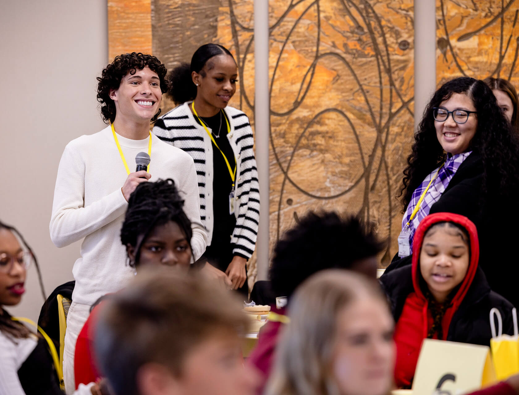Young people stand presenting with a microphone.