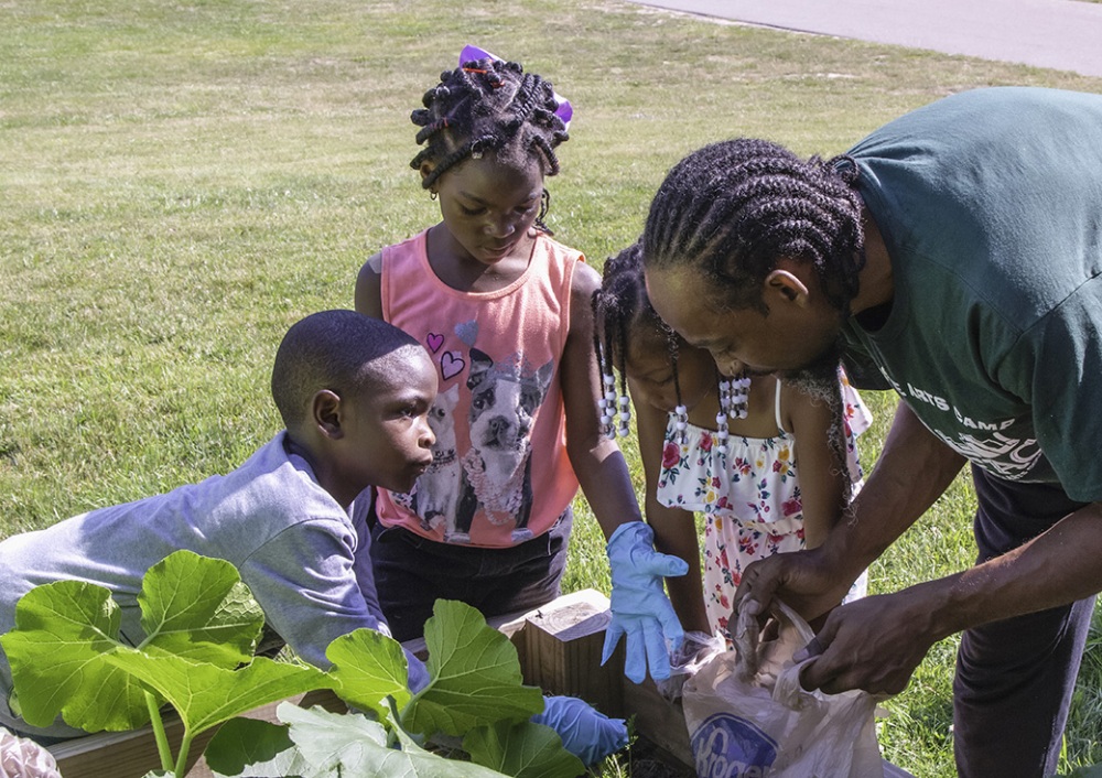 A man teaches children about planting a garden as part of an afterschool learning activity.