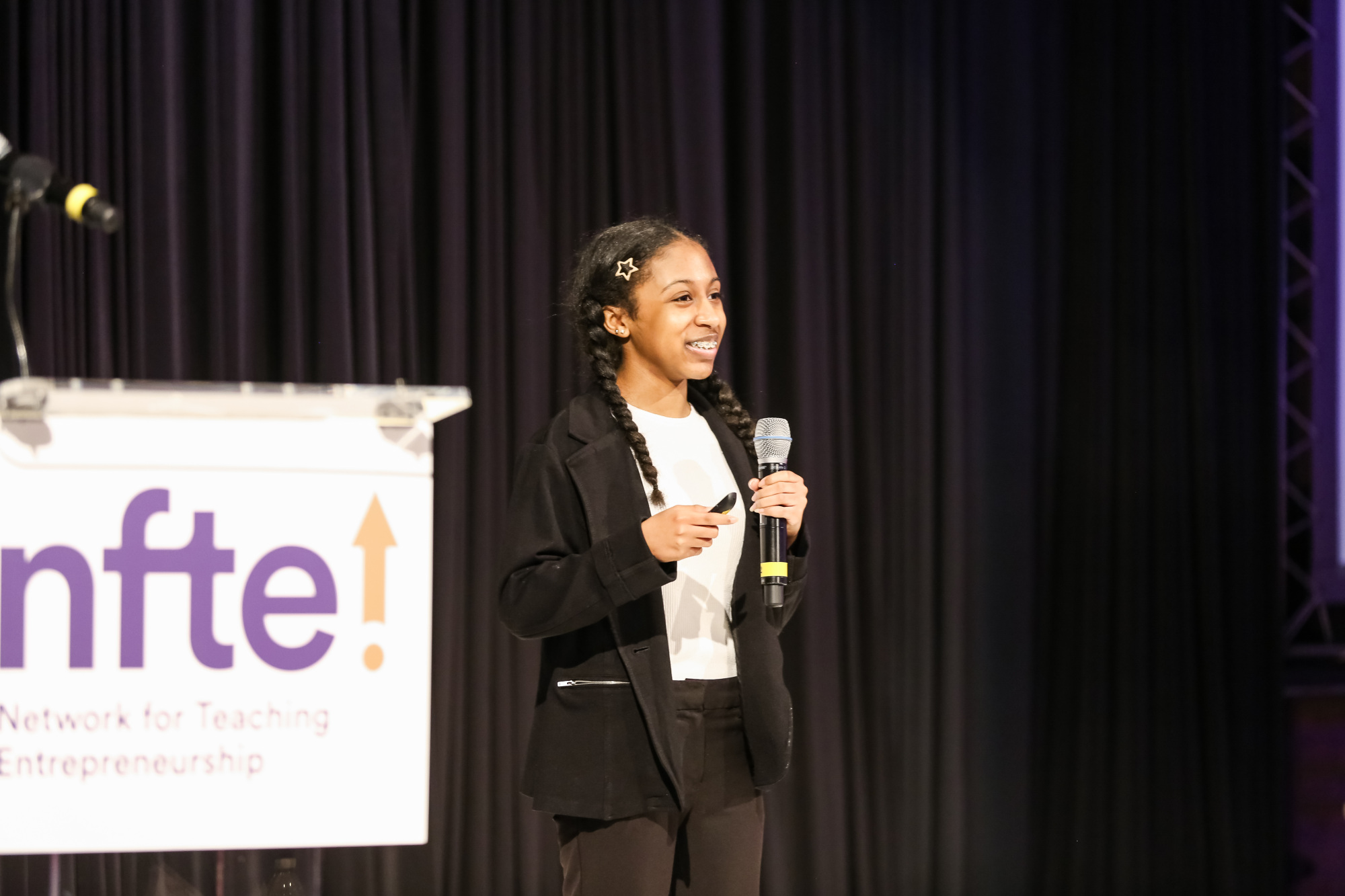 Student stands on stage speaking into a microphone