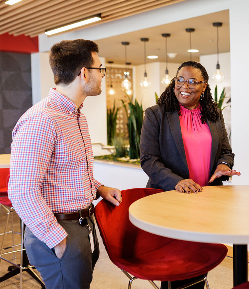 Two people gather around a table in an office setting.