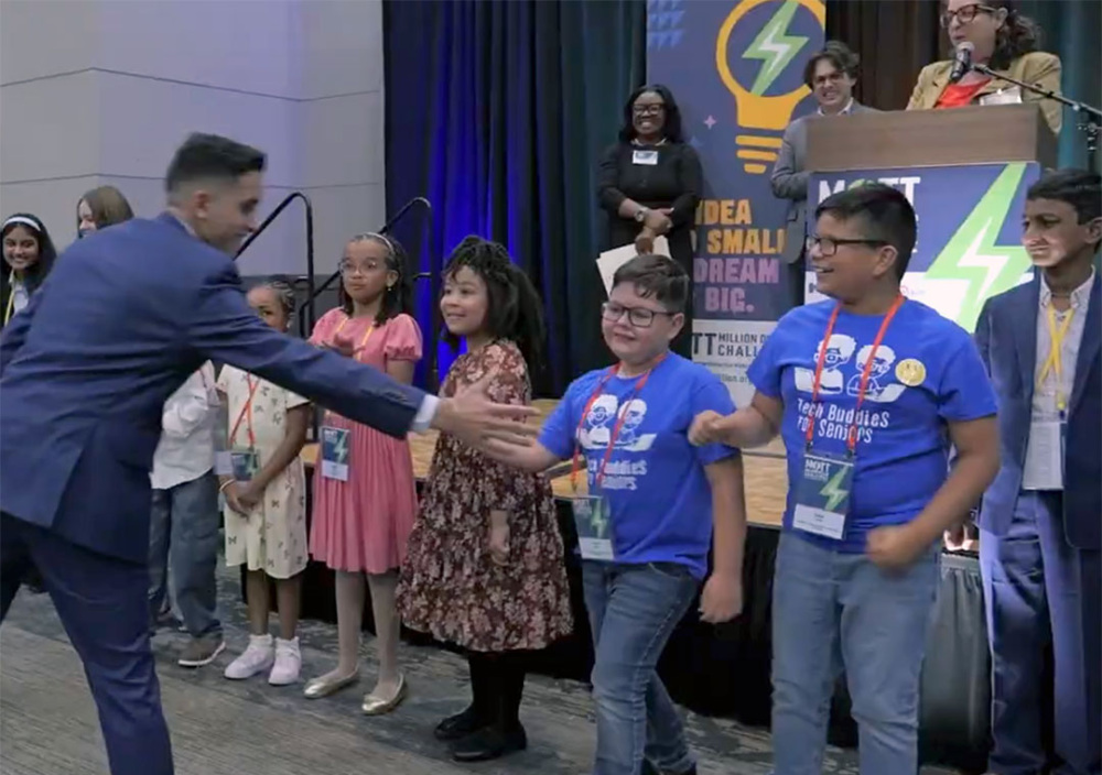 A row of kids at the Mott Million Dollar Challenge competition high five a man passing by.