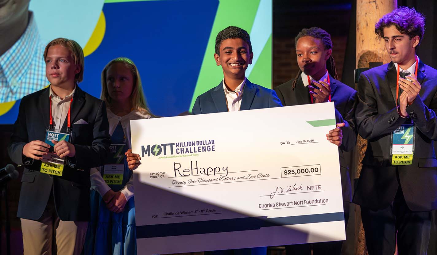 A student team stands on stage holding a $25,000 award check for ReHappy.