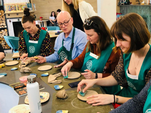 A seated group makes pottery plates.